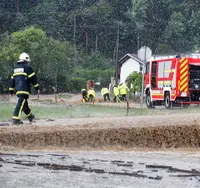 Firefighters at a road flooded after a storm