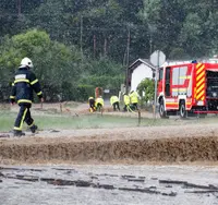 Firefighters at a road flooded after a storm